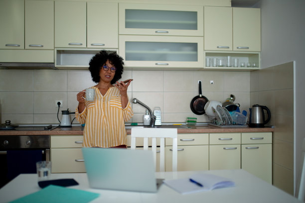 在厨房里居家办公的女性多任务处理 - 股票照片图片下载