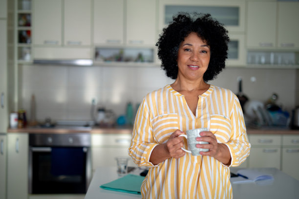非裔美国女性在家中微笑，享受咖啡 - 股票照片图片下载