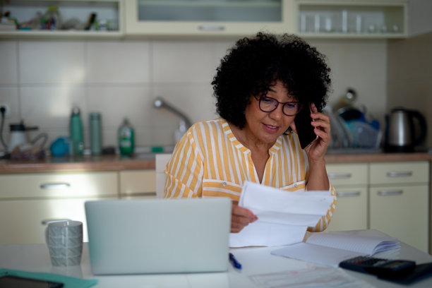 成熟的女性在电话中管理家庭财务 - 股票照片图片下载