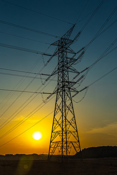 黑色电力输送塔的剪影，电缆在日落时分横跨天空。竖版照片图片下载