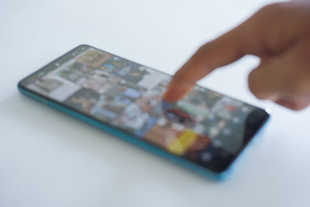 模糊的画面。一个人正在使用智能手机，浏览社交网络上的图片。特写镜头。手指在社交媒体应用的动态信息中滚动，进行信息搜索。图片下载