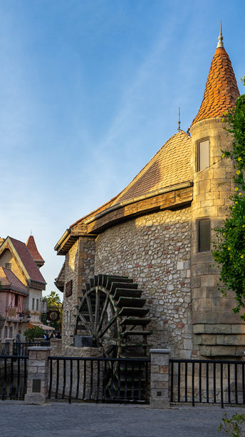 阿联酋的步行区，周围有商店和餐厅。迪拜的河岸乐园。中世纪欧洲风格的房屋和水车。竖版图片图片下载