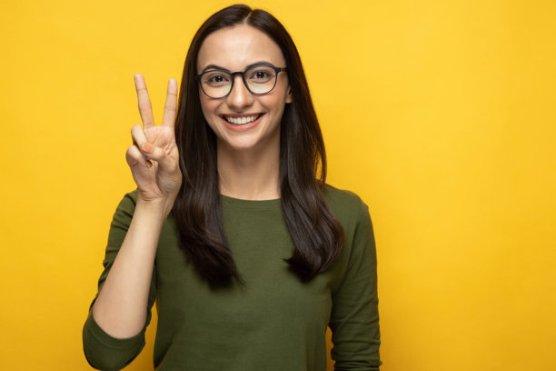 身穿绿色T恤的年轻女子肖像，背景为黄色，素材图片图片下载