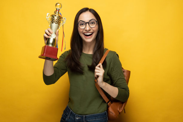 漂亮年轻的女学生，背着包，在黄色背景下孤立的照片素材图片下载