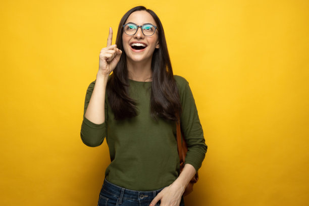 照片，一名漂亮的年轻女学生背着包，在黄色背景下孤立，素材照片图片下载