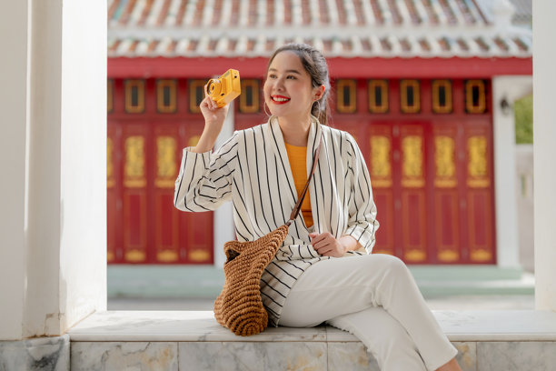 独自旅行的女性在古老寺庙中放松休息，在享受宁静的夏日文化探索之旅和真实的亚洲旅行体验的同时，回顾拍摄到的绝美照片。图片下载