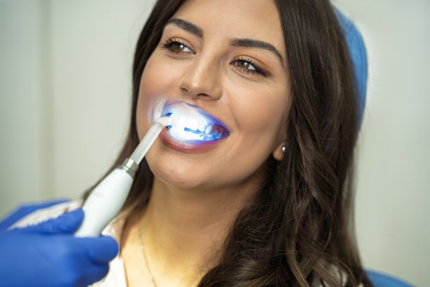 一位美丽的年轻女子带着甜美的笑容接受牙齿美白治疗图片下载