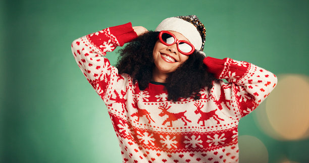 一位快乐的女士，身穿圣诞服装，戴着太阳镜，在绿色的背景下于影棚拍摄，营造节日气氛。照片捕捉了她脸部、作为女性人物或模特，带着笑容，适合十二月假期或庆祝活动的时尚圣诞老人形象，背景带有散景效果。图片下载