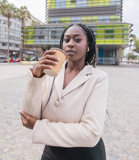 年轻的女商人一边喝咖啡一边摆姿势。竖直照片。图片下载