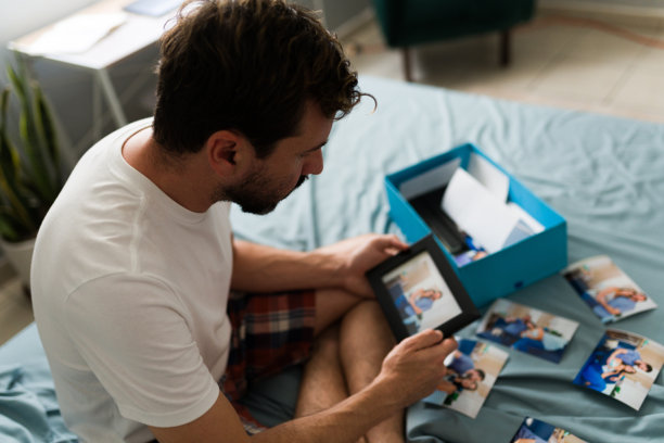 分手后在卧室里看着情侣照片的伤心男人图片下载