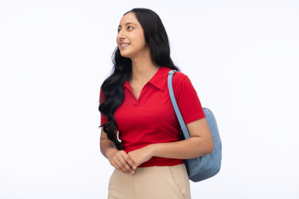 年轻女学生，身穿现代服装，肩背背包，在白色背景中拍摄的照片素材图片下载