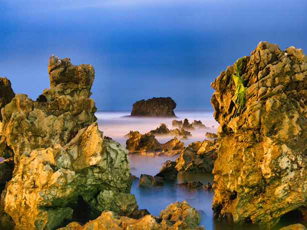 夜幕下的海岸岩石构造 - 戏剧性而神秘的长曝光照片，展示了锯齿状的海岸岩石构造，伴随着柔和如牛奶般的海水和深邃的蓝色暮光天空。西班牙，阿斯图里亚斯。图片下载