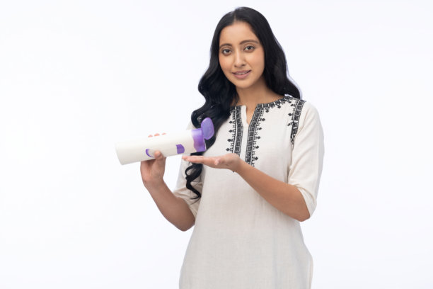 年轻快乐美丽的女孩，涂抹保湿霜，身穿库尔塔，在白色背景下拍摄的库存照片图片下载