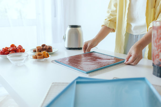 一位高加索女性正在厨房里准备自制的果脯，切新鲜水果作为健康的零食。该图片属于有机零食和自然生活系列。属于系列。图片下载