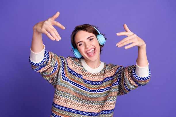 照片，一位戴着时髦衣服、听着音乐的快乐迷人女子，背景是孤立的紫色图片下载
