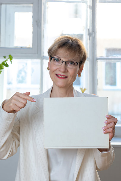 一名情绪化的女性肖像。自信的女性在白纸上用手指示方向，纸上留有文字空间。面向镜头，横幅。竖照片。图片下载