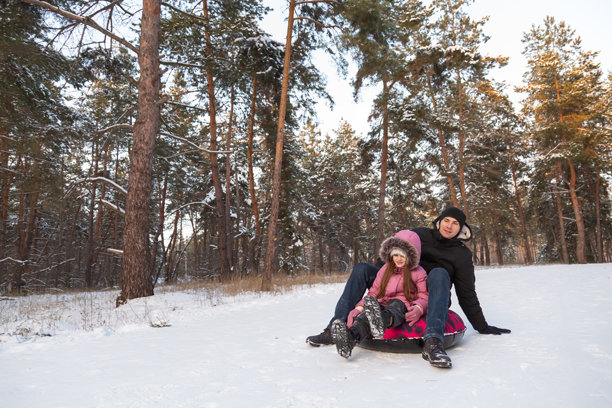 父亲和女儿在森林里玩雪管的图片，她们玩得很开心。图片下载