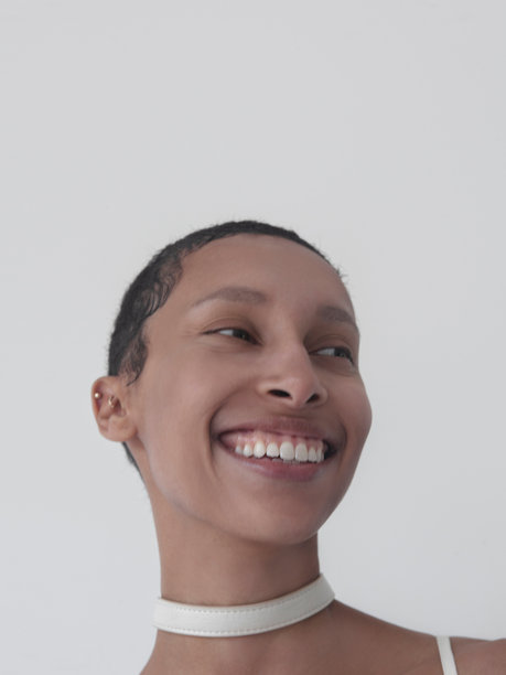 一位混血美女，笑容灿烂，表情引人注目，牙齿洁白，露出灿烂的笑容，近乎大笑。她是时尚模特，这是她的特写肖像照，展示了她的头部。她代表了多元化的多民族之美，包括非洲裔美国人、高加索人和白人。这张照片是在影棚拍摄的。图片下载