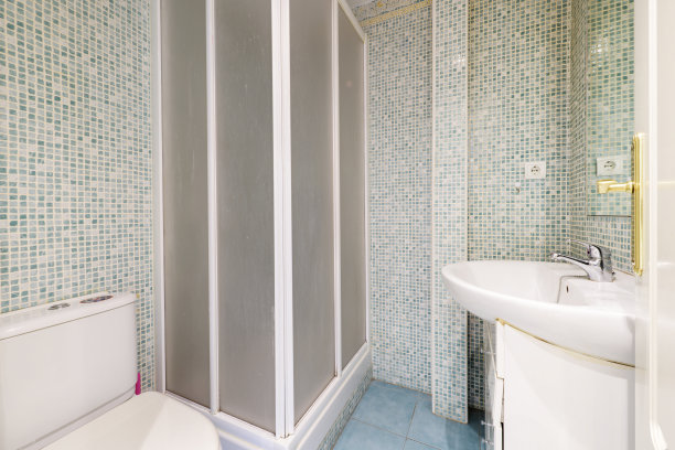 带有白色瓷器水槽、大理石台面、镀铬水龙头、无框镜子、白色淋浴间以及瓷砖墙壁的浴室图片下载