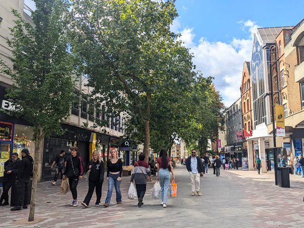 北安普顿，英格兰，阳光明媚、绿树成荫的商业街上，购物者和行人在悠闲地散步。图片下载