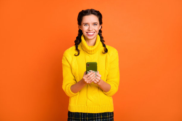 照片，迷人的、积极的女士，露出灿烂的笑容，看向镜头，身穿针织毛衣，背景是橙色，孤立的图片下载