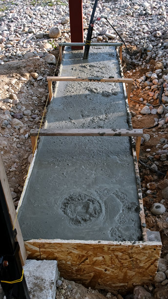 建筑工地上，湿混凝土被浇筑到模板中。水泥砂浆混合物。基础工程。基础侧视图。高质量照片图片下载