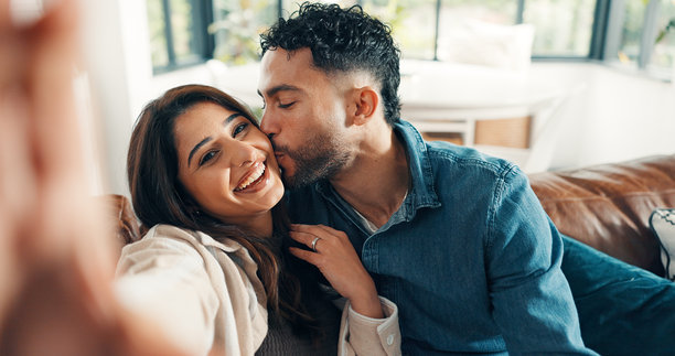 情侣在沙发上亲吻自拍，幸福地拥抱在一起，留下了婚姻的美好回忆。这张照片是他们爱情和放松的关系的写照，也是他们充满爱意的生活中的一个温馨的视角，适合作为个人资料照片。图片下载