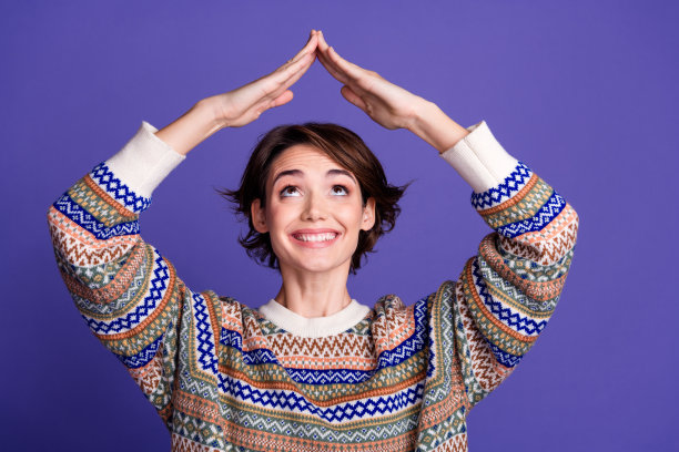 照片，一位穿着时尚服装，伸展双臂，上面有空白空间，孤立在紫色背景上的可爱、漂亮、开朗的女性。图片下载