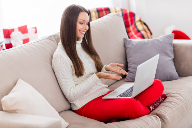 照片：可爱的漂亮年轻女子穿着针织毛衣，在室内房间家中用现代小工具交流，面带微笑。图片下载