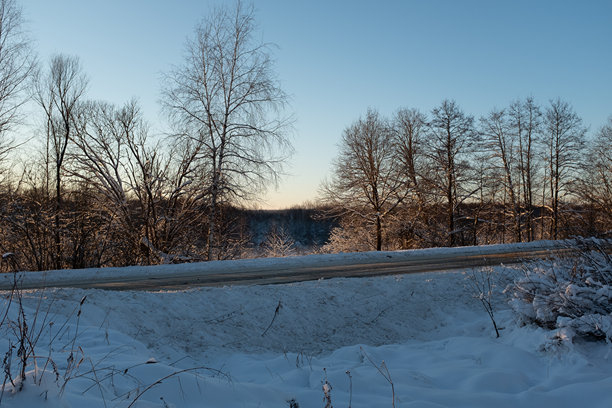 夕阳下，冬日森林中覆盖着雪的道路。高品质冬季风景照片，适用于出版物、海报、日历、帖子、屏保、壁纸、明信片、横幅、封面、网站图片。图片下载