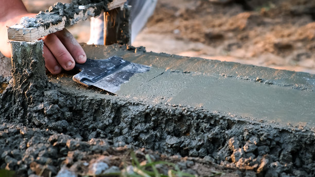 建筑工人在建筑工地上用抹子刮平模板上的湿混凝土。抹平以形成平整表面。专业的地面基础手工。高质量照片图片下载