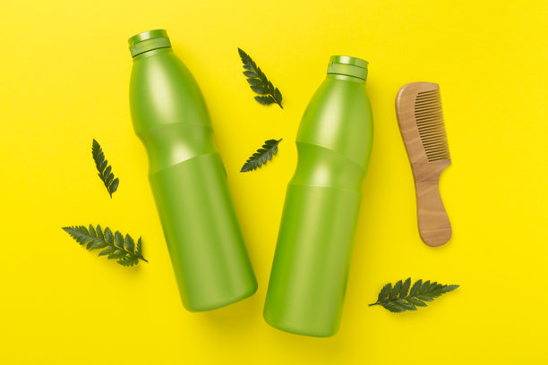 洗发水和发膜，背景为绿色叶子，俯视图片下载