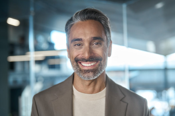 一位快乐的中年商务男士在办公室看向镜头，拍摄的是头像照片。图片下载