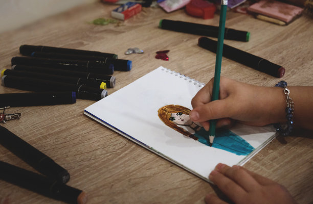 儿童和青少年在绘制有趣的草图。手绘动漫风格女孩素描，使用酒精性马克笔进行创作和着色。漫画书。动漫。青年文化。图片下载