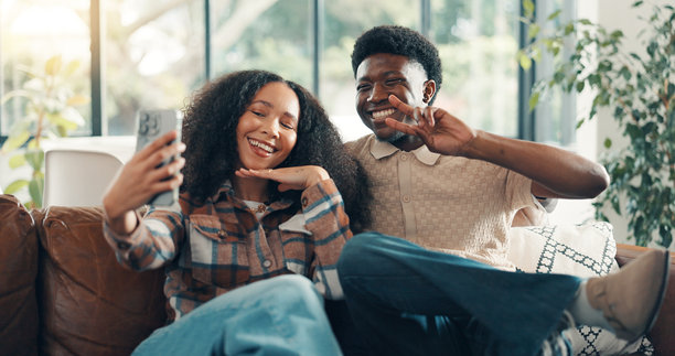 家居，沙发上的情侣自拍，爱与连接，比着和平手势，放松与浪漫。公寓，个人资料图片，男女在一起，关系与回忆，充满幸福、微笑与手势。图片下载