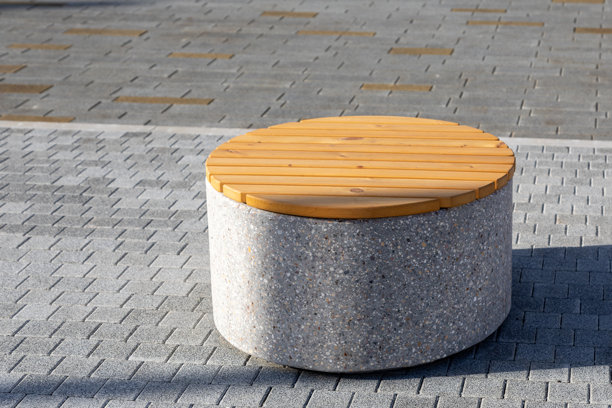 铺砌的人行道上的圆形长椅，带有混凝土底座和木质座椅。城市环境中的休息场所。照片图片下载