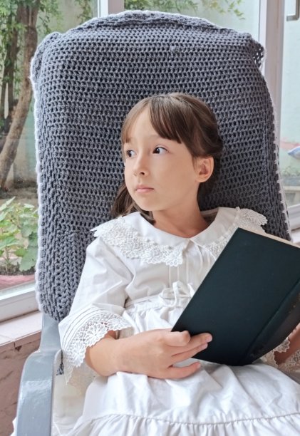 身穿白裙的小女孩坐在椅子上看书，复古风格图片下载