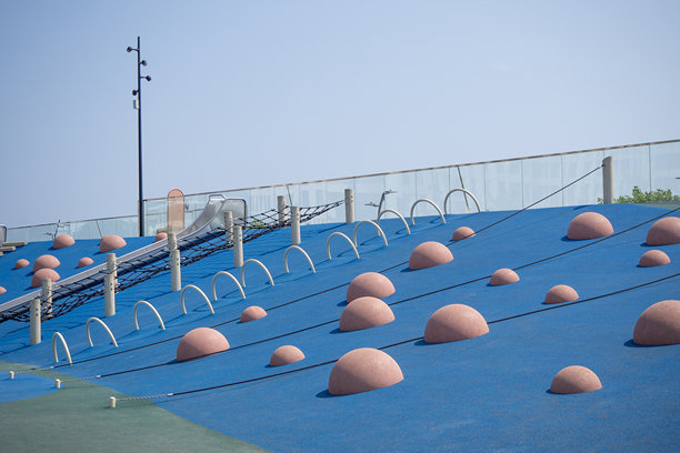 蓝色的软质安全地垫，配有攀爬圆顶和网状结构。现代化城市户外儿童游乐场。照片。图片下载