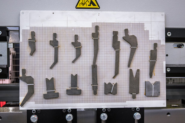 冲床模具、冲压模具和冲头集合，在网格板上排列整齐，工业金属加工设备，专业的钣金制造工具图片下载