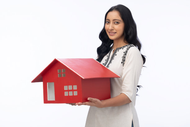 年轻女子身穿库尔塔，手持房屋模型，在白色背景下拍摄的照片素材图片下载