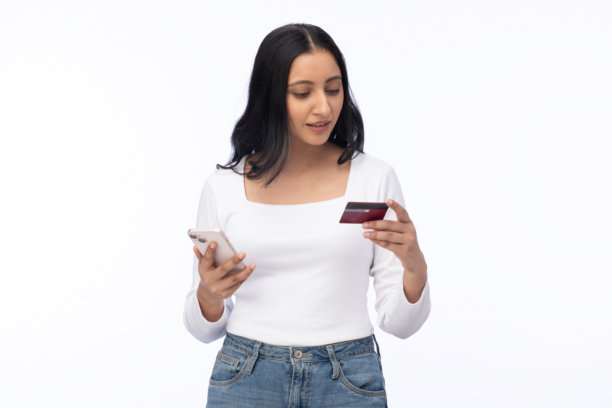 年轻女子手持信用卡和智能手机，白色背景，购物素材图片下载