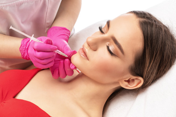 美容师为女性进行瘦脸针注射，以燃烧下巴、脸颊和颈部的脂肪，对抗双下巴。美容院中的女性美容疗程。美容概念。图片下载
