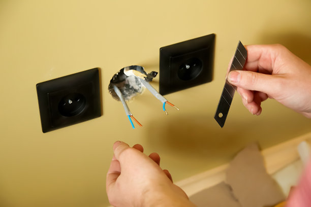 一名电工正在用刀精确切割。这张照片聚焦于男子的手，非常适合用于现代安装的布线和电路主题。图片下载