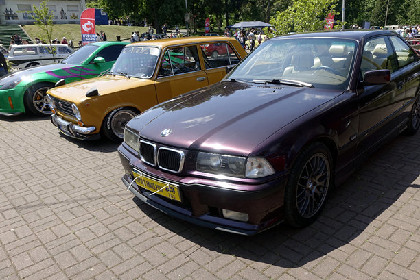 阳光明媚的户外汽车聚会上展示的经典宝马E36和伏尔加汽车图片下载