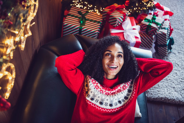 从高处拍摄的正面照片，一个人躺在沙发上，双手放在脑后，沉思着圣诞节的童话时光，室内平铺。图片下载