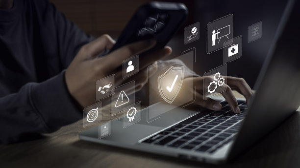 特写双手使用笔记本电脑和智能手机，屏幕上的数字界面图标象征着现代科技环境下的工作场所安全、数字治理、合规监控和风险控制。图片下载