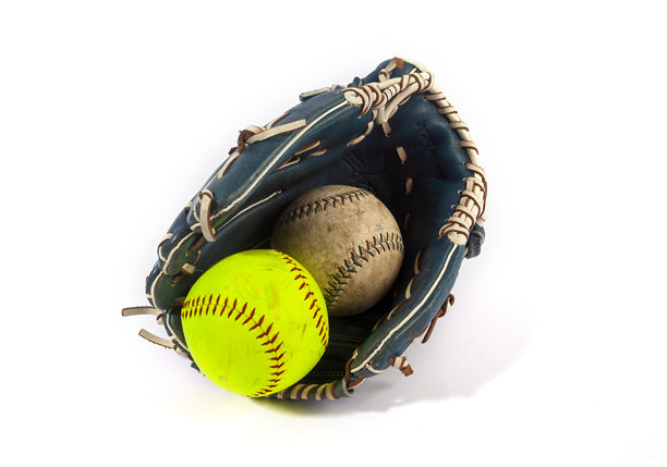 一个旧棒球和一颗亮黄色的垒球放在一个皮手套里。这张图片在白色背景下孤立地展示了两种相似、受欢迎的运动的经典装备，并进行了对比。图片下载