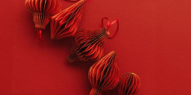 节日红色纸质圣诞装饰品，悬挂着带有金色光泽的红色手电筒或灯笼，背景为红色，极简风格美学单色照片，节日主题俯视横幅，可留白。图片下载