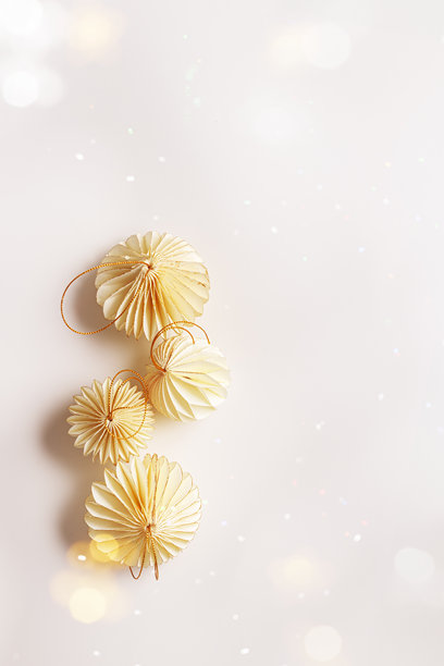 纸质新年装饰品的平面图，金色米色圣诞球在浅白色背景上，冬季节日庆祝静物。简约照片，优雅的节日装饰，俯视，留白 copyspace。图片下载