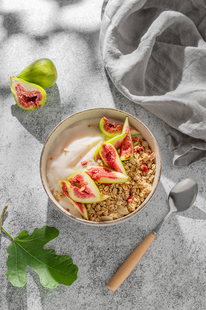 碗装天然酸奶配谷物或麦片、无花果和蜂蜜，置于灰色背景上。图片下载